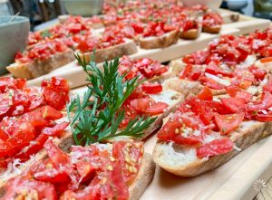 Mehrere Holzbretter hintereinander auf denen Bruschettabrote angerichtet sind.