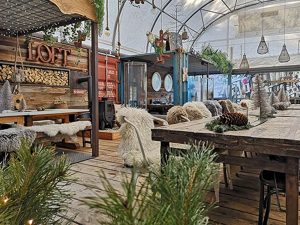 Wintergarten/Loft mit rustikalen Holztischen und gemütlichen Schaffellen auf den Sitzmöbeln